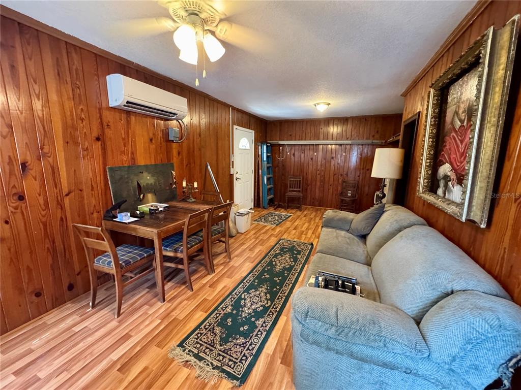 A living room features wood-paneled walls, a dining table, a sofa, and a ceiling fan — 1215 NW 12TH AVENUE, GAINESVILLE, FL