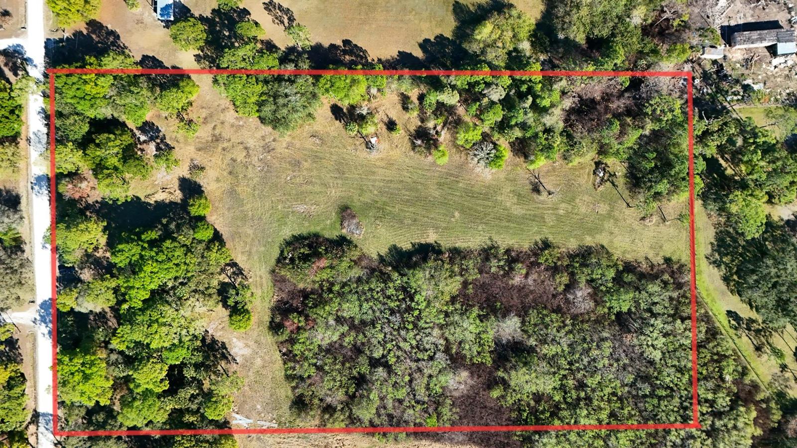An aerial view shows a rectangular plot of land featuring a mix of grassy fields and trees — 13822 Hamlin Avenue, Clewiston FL 33440, CLEWISTON, FL