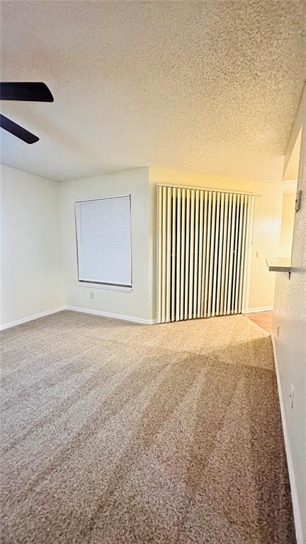 A carpeted living room features a ceiling fan, a window with blinds, and vertical blinds — 1017 S HIAWASSEE ROAD UNIT 3716, ORLANDO, FL