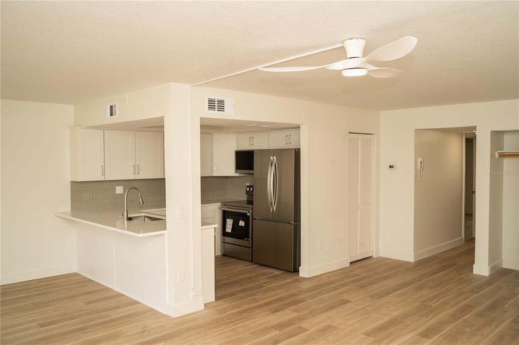 A kitchen with white cabinets, stainless steel appliances, and light wood-look flooring — 661 POINSETTIA AVENUE UNIT 108, CLEARWATER BEACH, FL