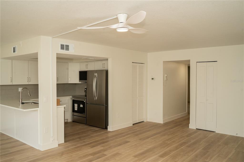 A kitchen with stainless steel appliances and white cabinets opens into a living area — 661 POINSETTIA AVENUE UNIT 108, CLEARWATER BEACH, FL
