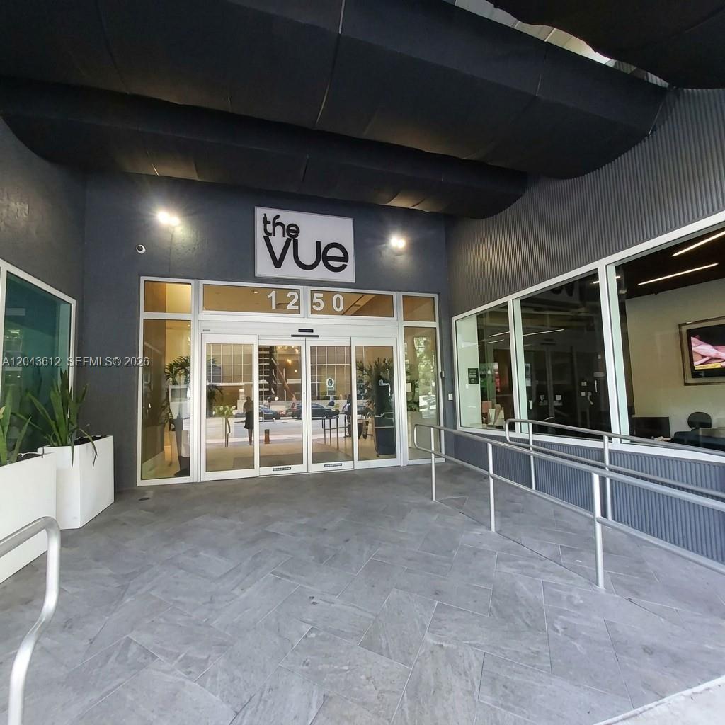 The exterior entrance of a building features a glass door, metal railings, and grey tiling — 1250 S Miami Ave # 1311, Miami FL 33130, MIAMI, FL