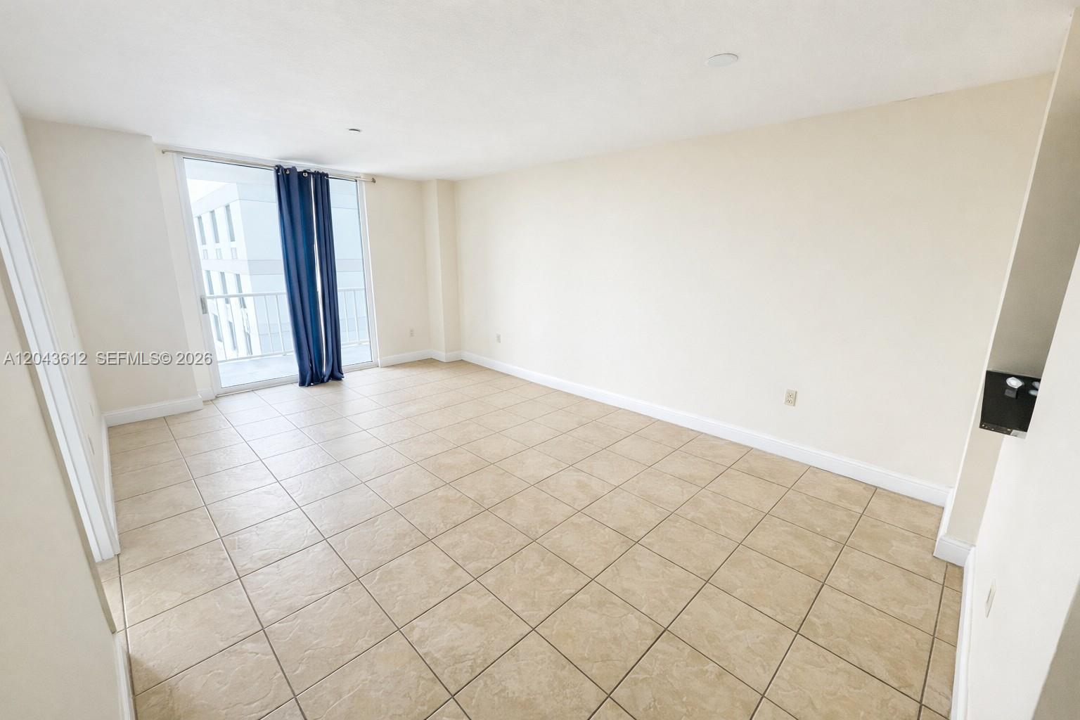 An empty room features beige tile flooring, white walls, and a sliding glass door — 1250 S Miami Ave # 1311, Miami FL 33130, MIAMI, FL