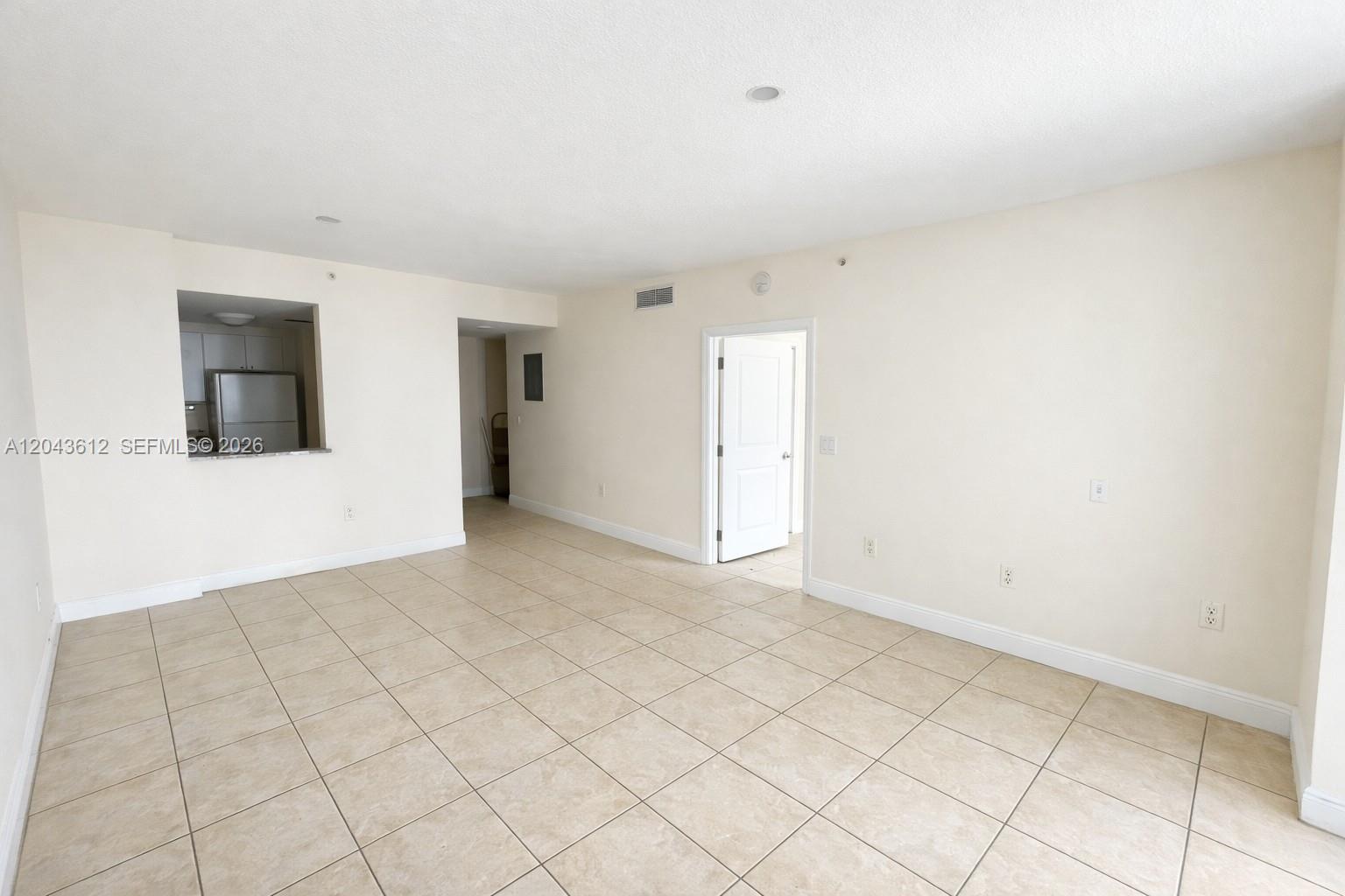 An empty room features beige tile flooring, white walls, and an open kitchen pass-through — 1250 S Miami Ave # 1311, Miami FL 33130, MIAMI, FL
