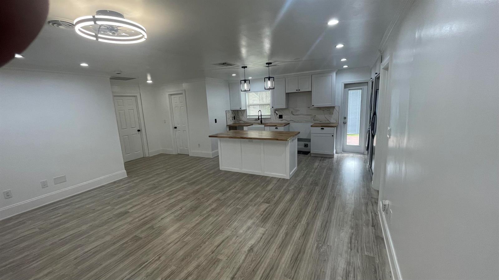 A kitchen with white cabinets, a wood-topped island, and light wood-look flooring — 4779 Bonanza Road, Lake Worth FL 33467, LAKE WORTH, FL