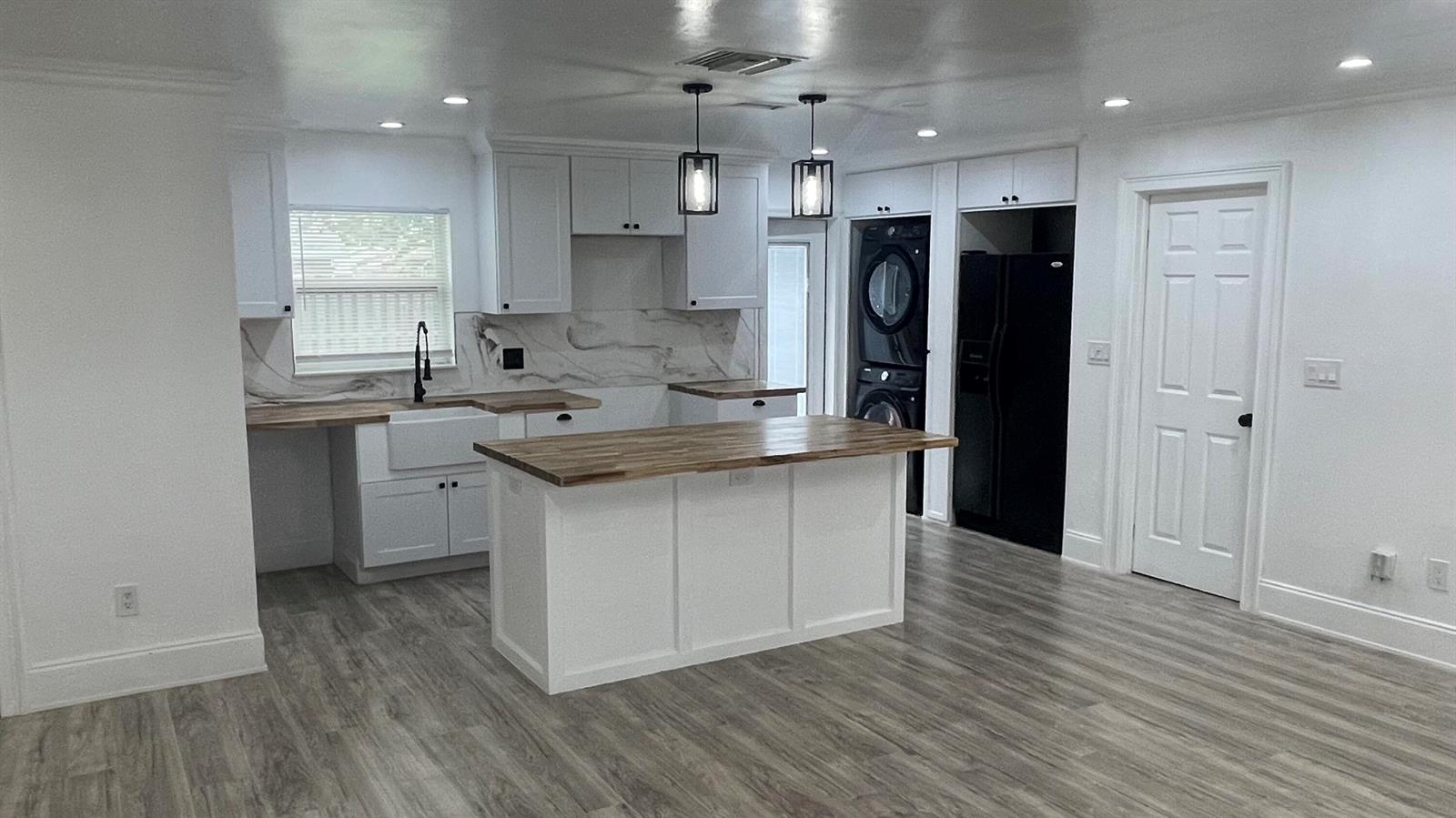A kitchen features white cabinets, a wood-topped island, black appliances, and light wood-look flooring — 4779 Bonanza Road, Lake Worth FL 33467, LAKE WORTH, FL