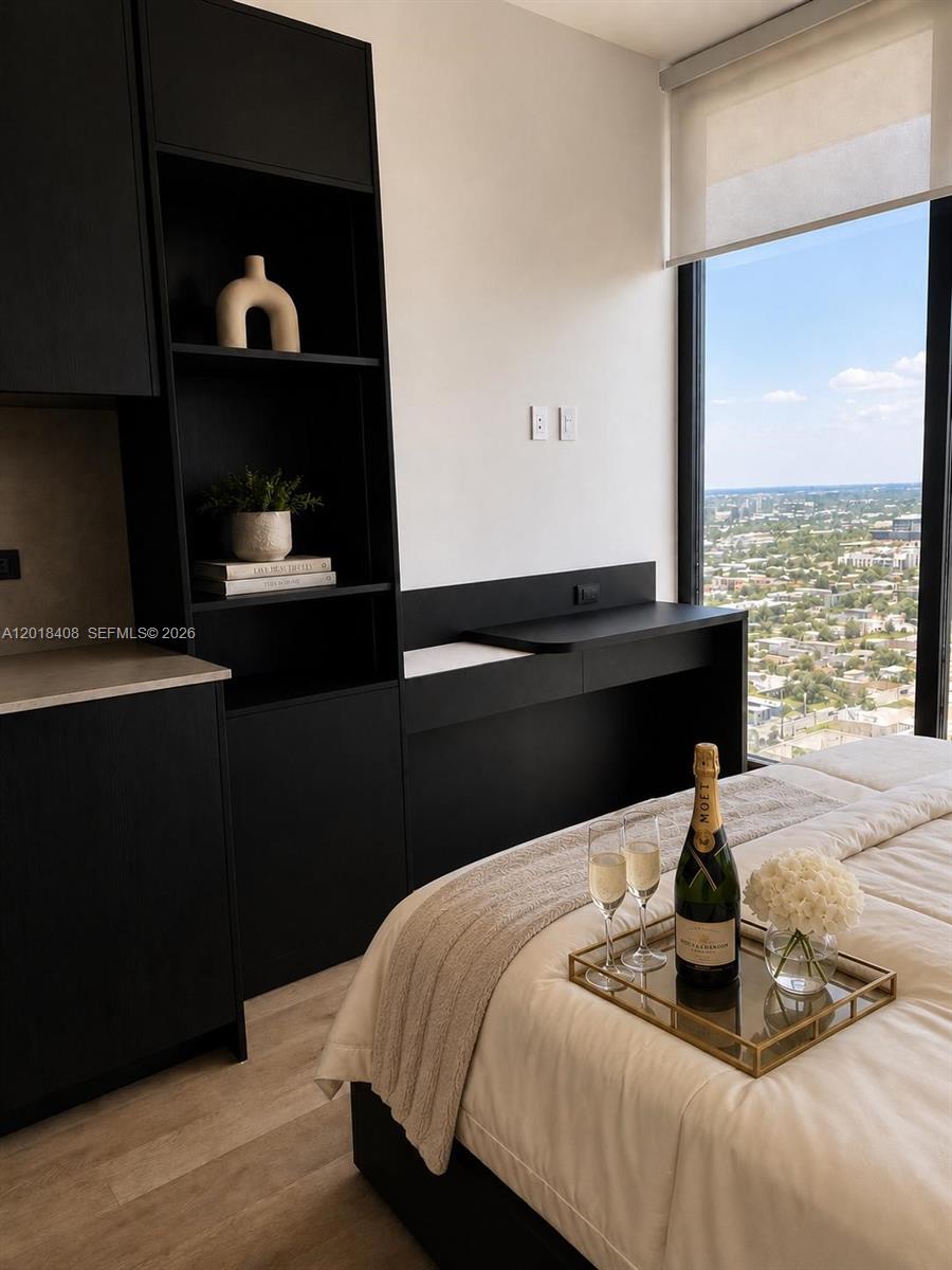 A bedroom features black cabinetry, a desk, and a bed with champagne on a tray — 20 NE 11th # 4203A, Miami FL 33132, MIAMI, FL