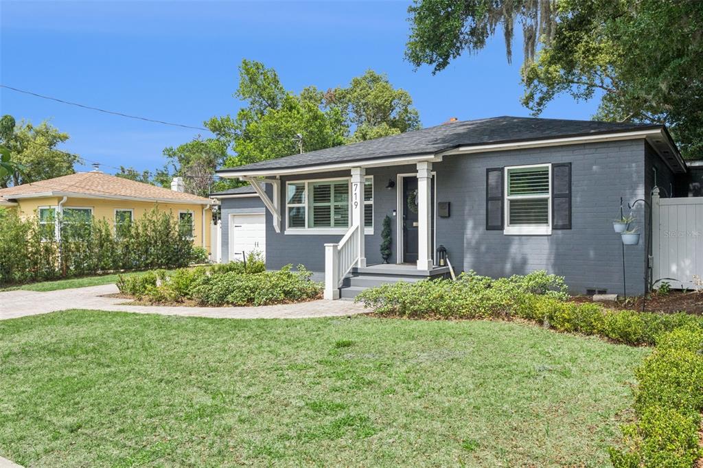 A gray brick house with a white porch and a paved walkway sits on grass — 719 WARWICK PLACE, ORLANDO, FL