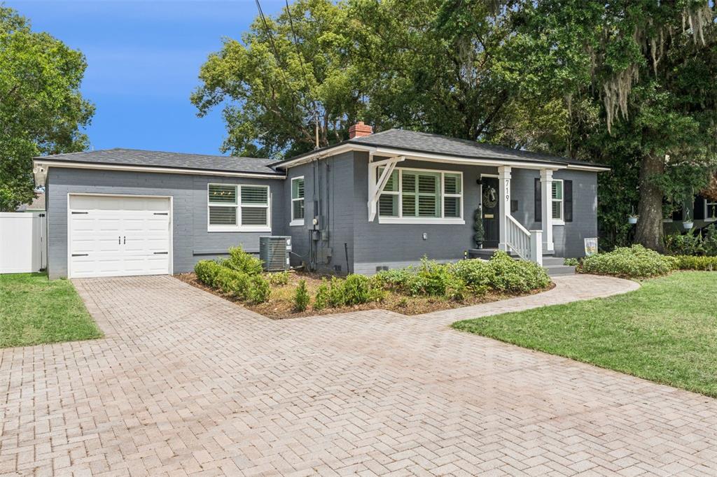 A gray brick house with a white garage door, front porch, and paved driveway — 719 WARWICK PLACE, ORLANDO, FL