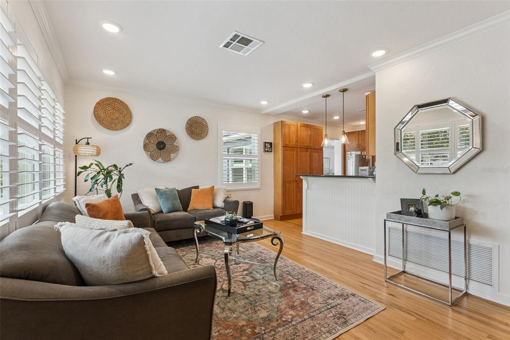 A living room with hardwood floors, a brown sofa, a glass coffee table, and kitchen access — 719 WARWICK PLACE, ORLANDO, FL