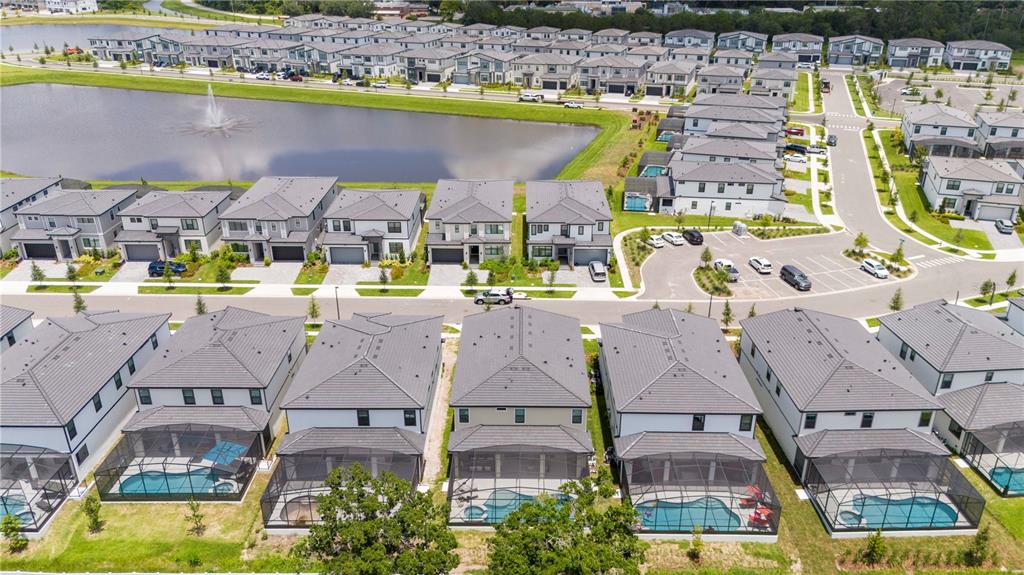 An aerial view shows a suburban neighborhood with houses, swimming pools, and a central pond — 5887 HIGH SEAS DRIVE, ORLANDO, FL