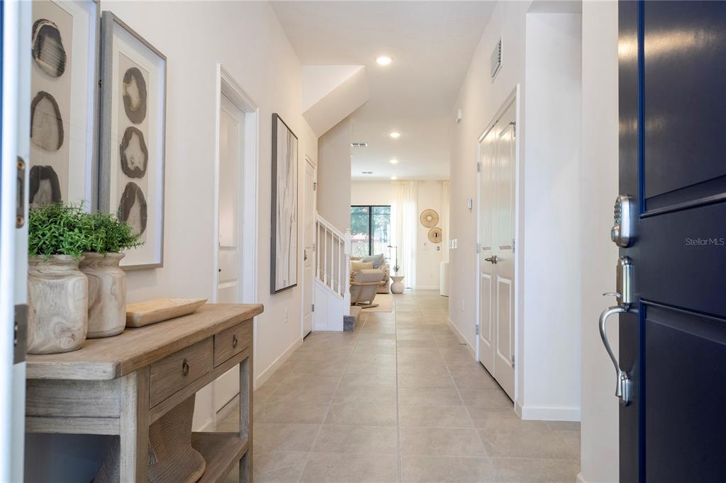 A bright entryway features tile flooring, a wooden console table, and a view toward stairs — 5887 HIGH SEAS DRIVE, ORLANDO, FL