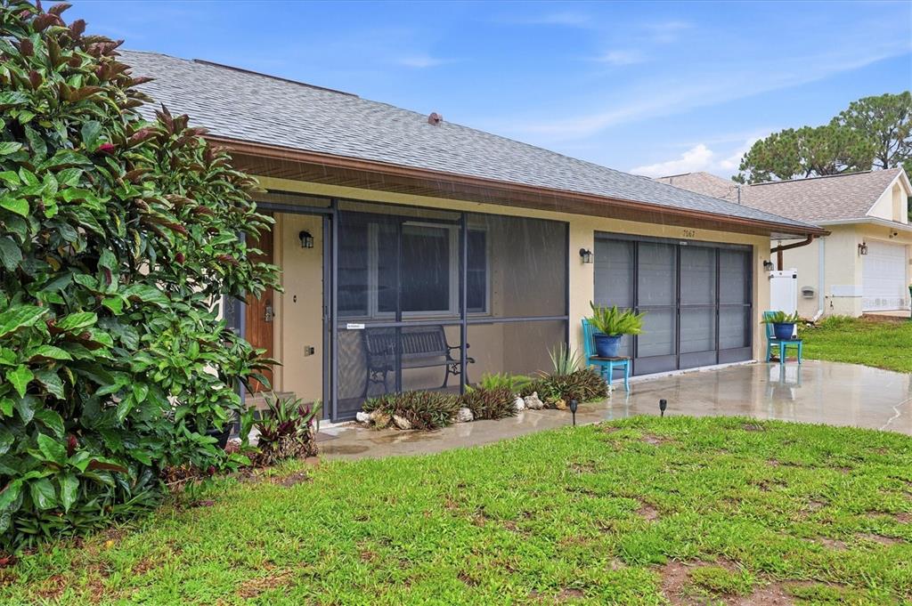 A single-story house exterior features a screened-in porch, a concrete driveway, and a grassy lawn — 7067 NATALIE STREET, ENGLEWOOD, FL