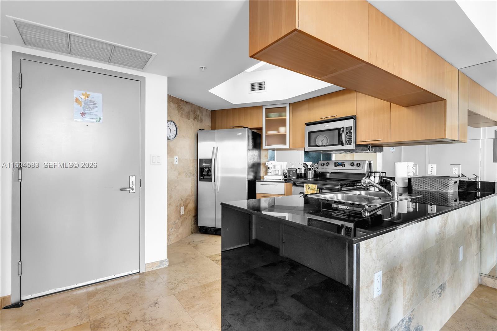 A kitchen features light wood cabinets, black granite countertops, stainless steel appliances, and tile flooring — 1750 N Bayshore Dr # 5014, Miami FL 33132, MIAMI, FL