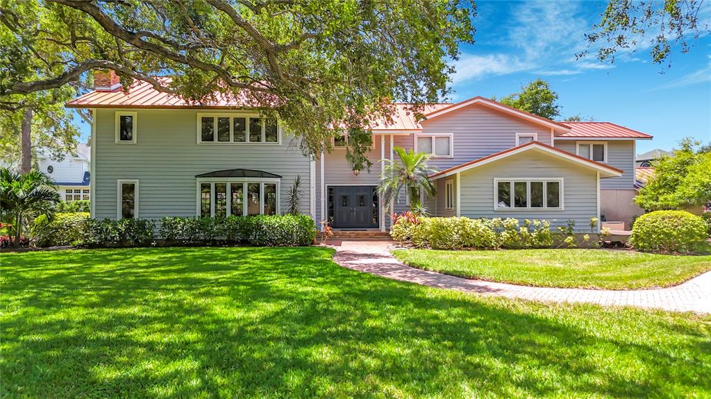 A two-story house with light gray siding, a red metal roof, and a paved walkway — 8005 17TH AVENUE W, BRADENTON, FL
