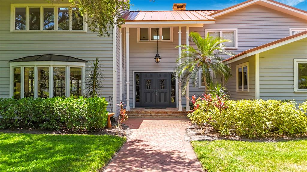 A gray two-story house features a brick walkway leading to a double front door — 8005 17TH AVENUE W, BRADENTON, FL