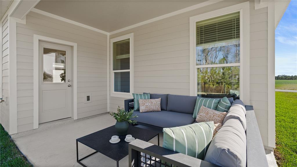 A covered patio features light-colored siding, a door, two windows, and outdoor sectional seating — 5551 GUAVA COURT, KISSIMMEE, FL