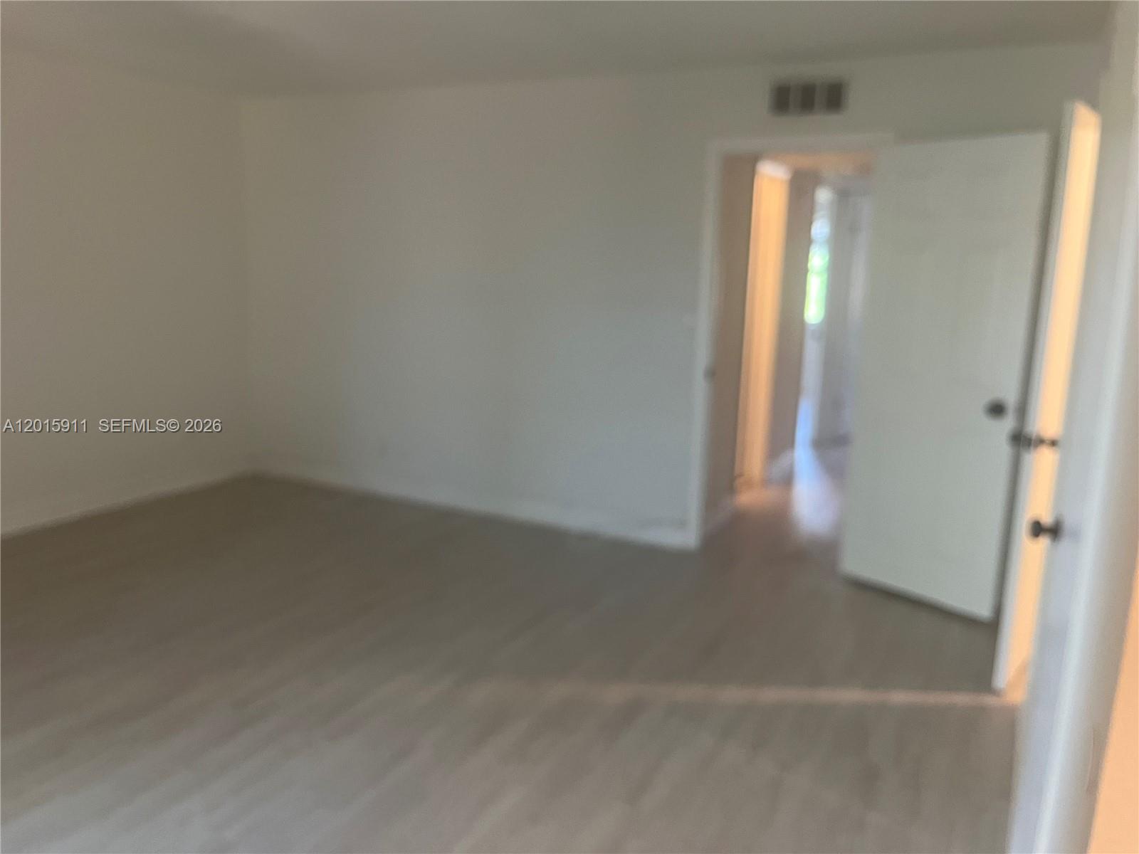 An empty room features light-colored wood-look flooring and a doorway leading to a hallway — 5952 NW 25th Pl # 234, Sunrise FL 33313, SUNRISE, FL