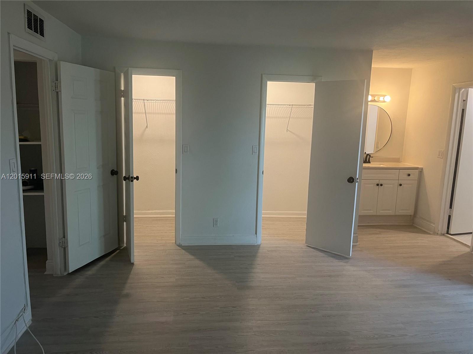 A room features light wood-look flooring, two open closets, and an adjacent bathroom vanity area — 5952 NW 25th Pl # 234, Sunrise FL 33313, SUNRISE, FL