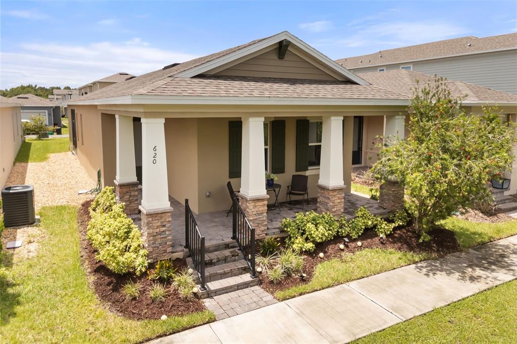 The exterior of a single-story house features a covered front porch with stone-based columns — 620 BAYERN LANE, DEBARY, FL