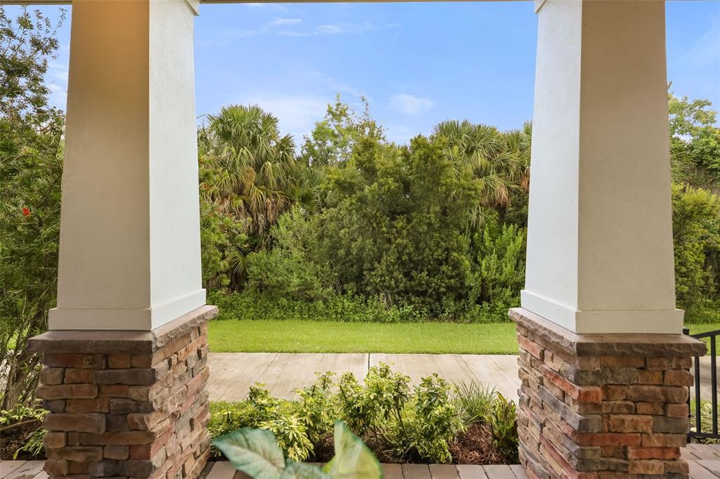 A view from a covered porch looking out toward a lawn and dense green trees — 620 BAYERN LANE, DEBARY, FL