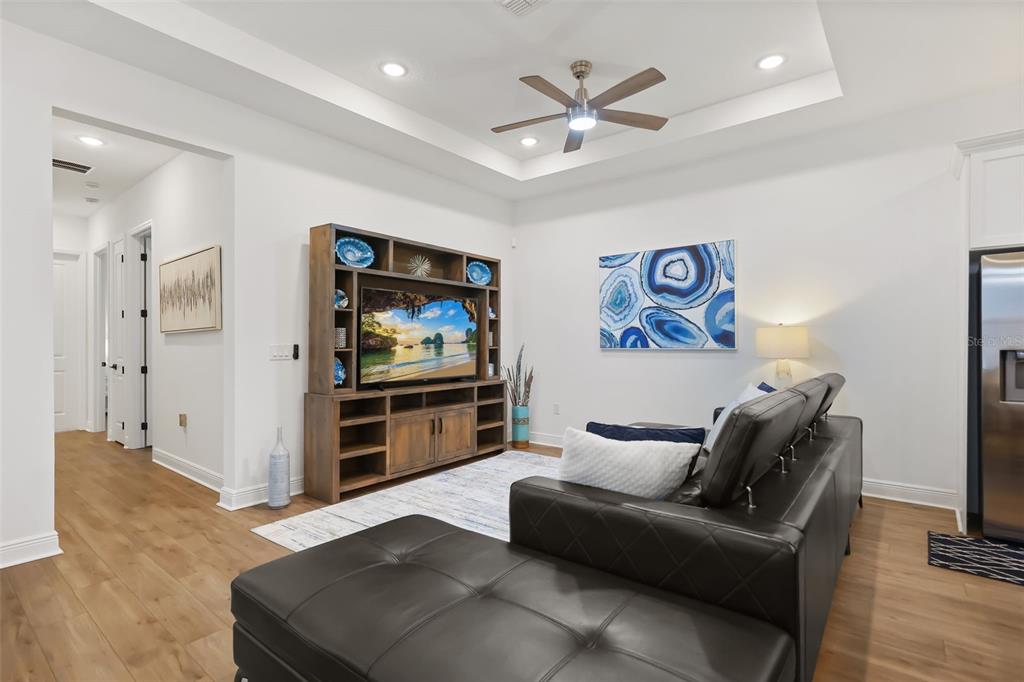 A living room features a tray ceiling, wood-look flooring, a large entertainment center, and sectional — 620 BAYERN LANE, DEBARY, FL