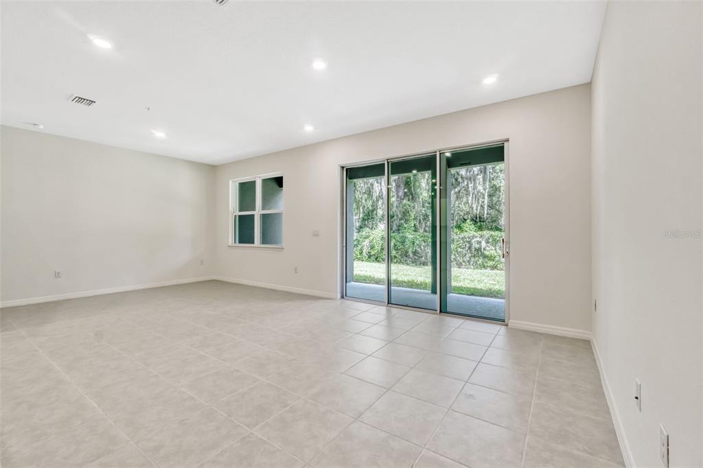 An empty room features light-colored tile flooring, recessed lighting, and a sliding glass door — 5213 LUISA COURT, ST CLOUD, FL