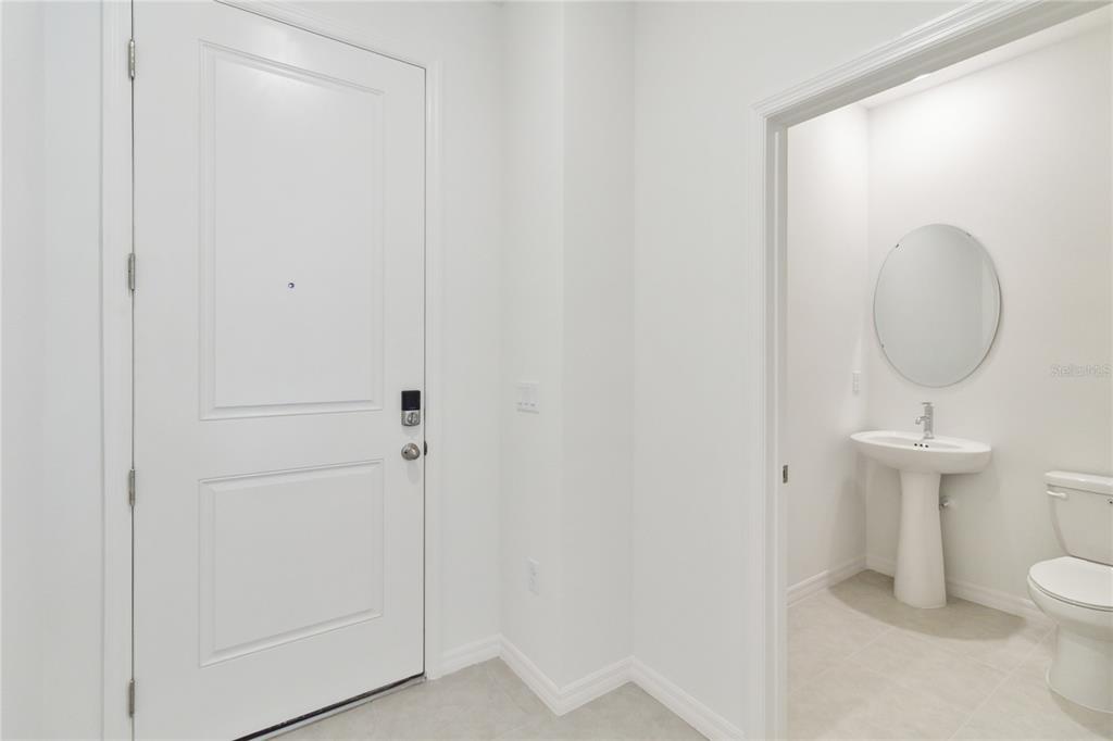 A white door stands next to a small bathroom featuring a pedestal sink and mirror — 5213 LUISA COURT, ST CLOUD, FL