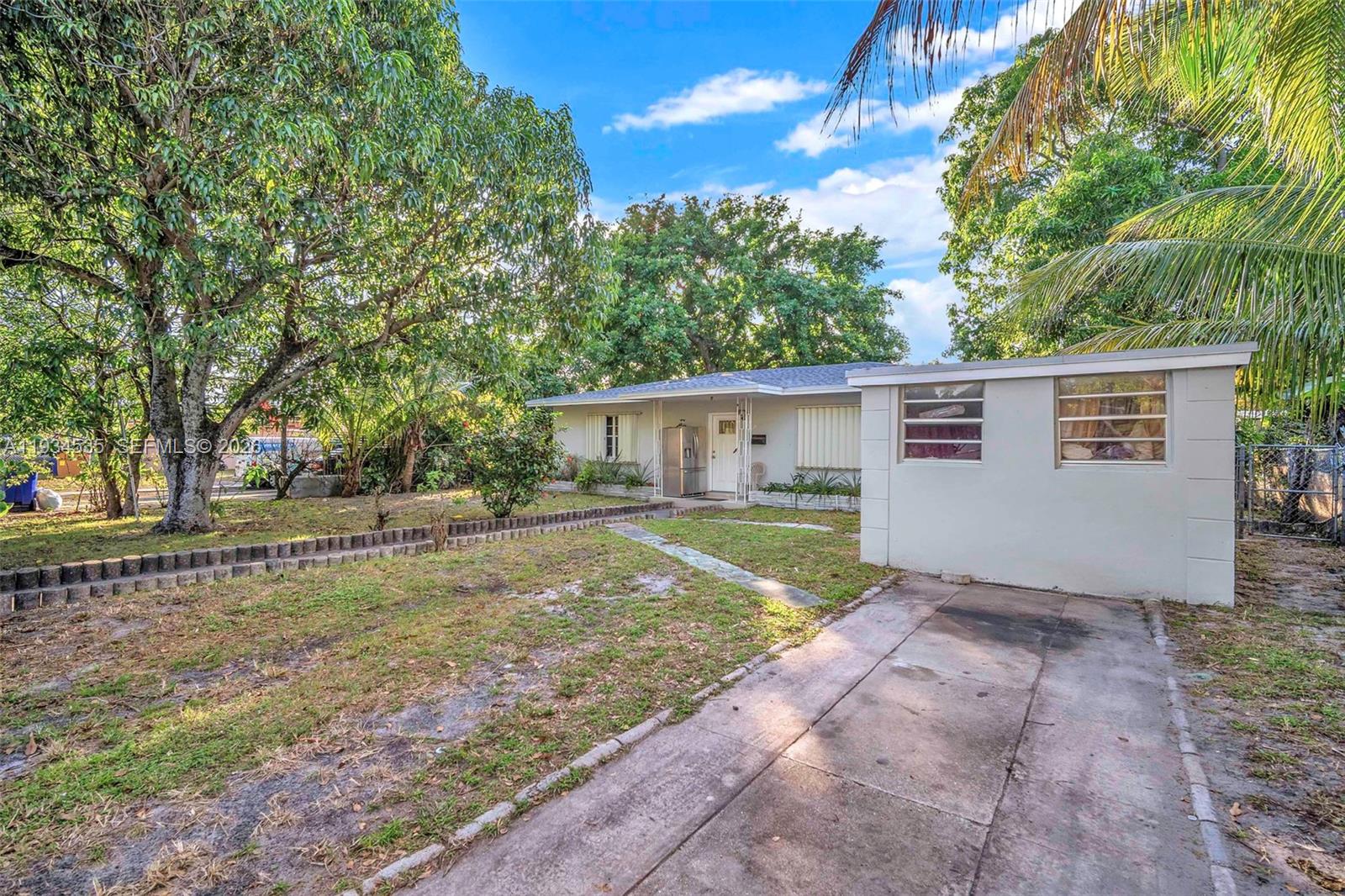 A single-story house with a concrete driveway, a small detached structure, and mature trees — 16234 NE 9th Ct, North Miami Beach FL 33162, NORTH MIAMI BEACH, FL