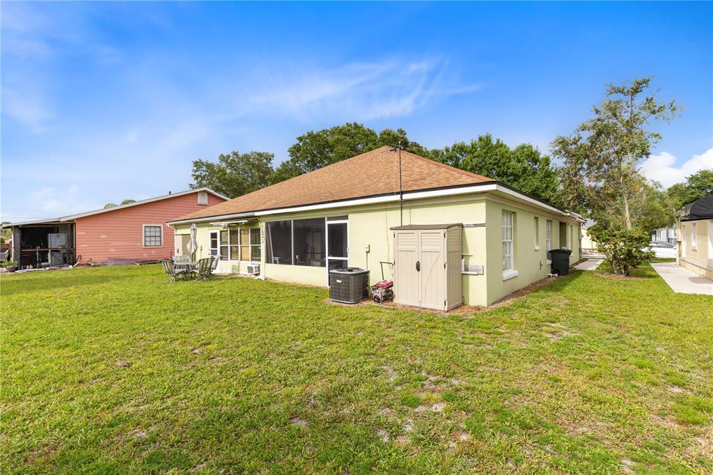The exterior of a light green house with a screened-in porch and a storage shed — 1076 UNIVERSAL REST PLACE, KISSIMMEE, FL