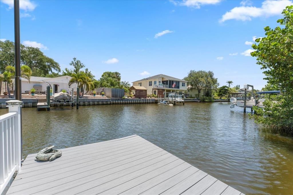 A view from a wooden dock looking across a canal toward houses and boats — 344 CROSSWINDS DRIVE, PALM HARBOR, FL
