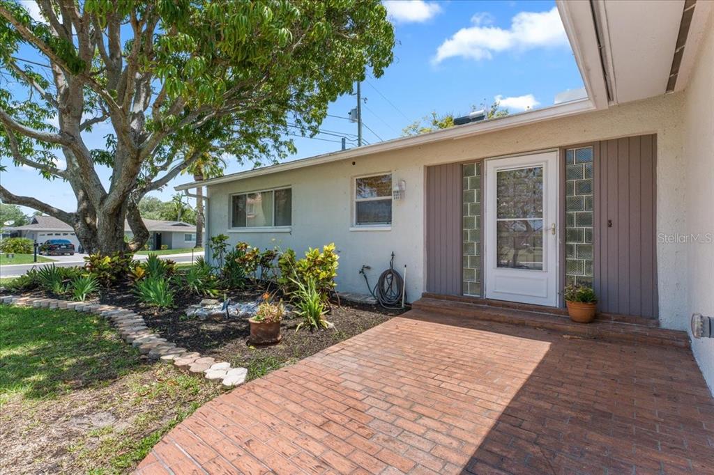 A brick patio leads to the front entrance of a single-story home with landscaping — 344 CROSSWINDS DRIVE, PALM HARBOR, FL