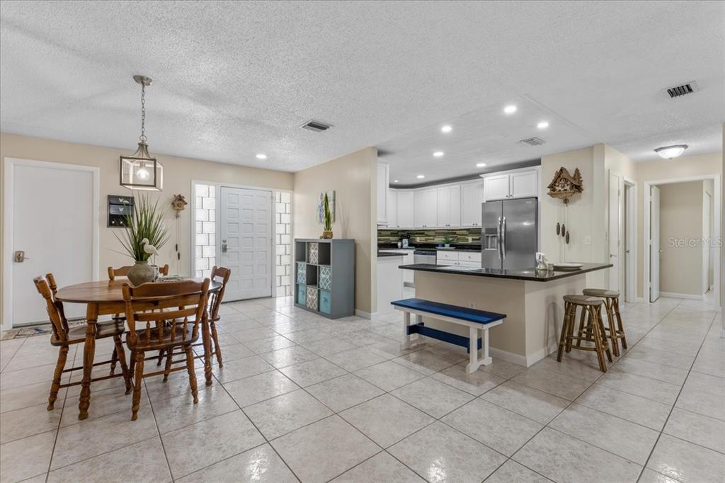 An open-concept kitchen and dining area features tile flooring, white cabinetry, and a breakfast bar — 344 CROSSWINDS DRIVE, PALM HARBOR, FL
