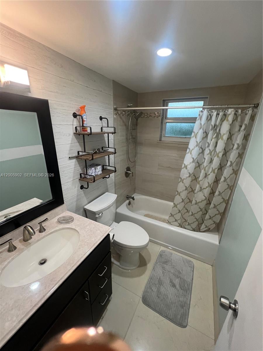 A bathroom features a vanity, toilet, and a bathtub with a shower curtain — 9945 SW 164th Ter # 1, Miami FL 33157, MIAMI, FL