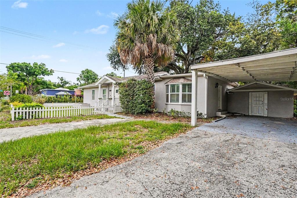 A single-story house with a white picket fence, a palm tree, and a carport — 4809 N HIGHLAND AVENUE, TAMPA, FL