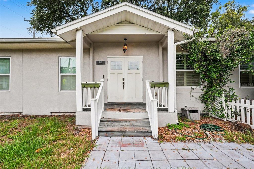 The exterior of a house features a covered front porch with white railings and double doors — 4809 N HIGHLAND AVENUE, TAMPA, FL