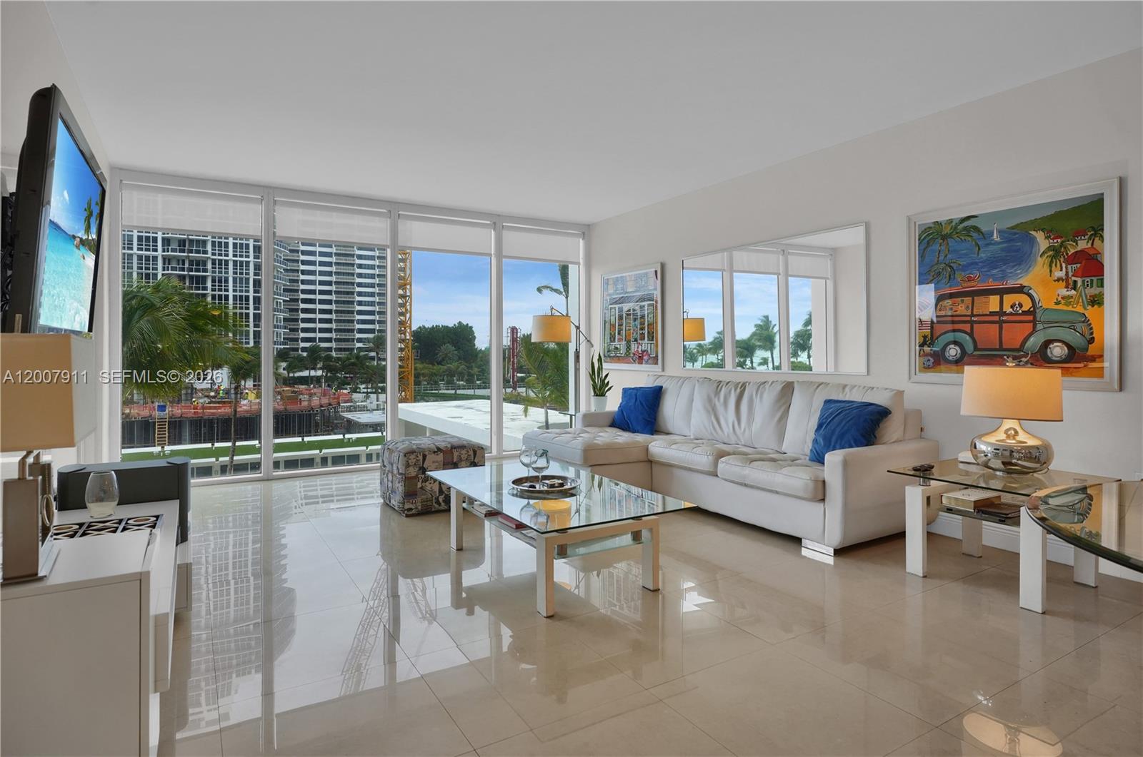 A living room features a white sectional sofa, glass coffee table, and floor-to-ceiling windows — 10275 Collins Ave # 315, Bal Harbour FL 33154, BAL HARBOUR, FL