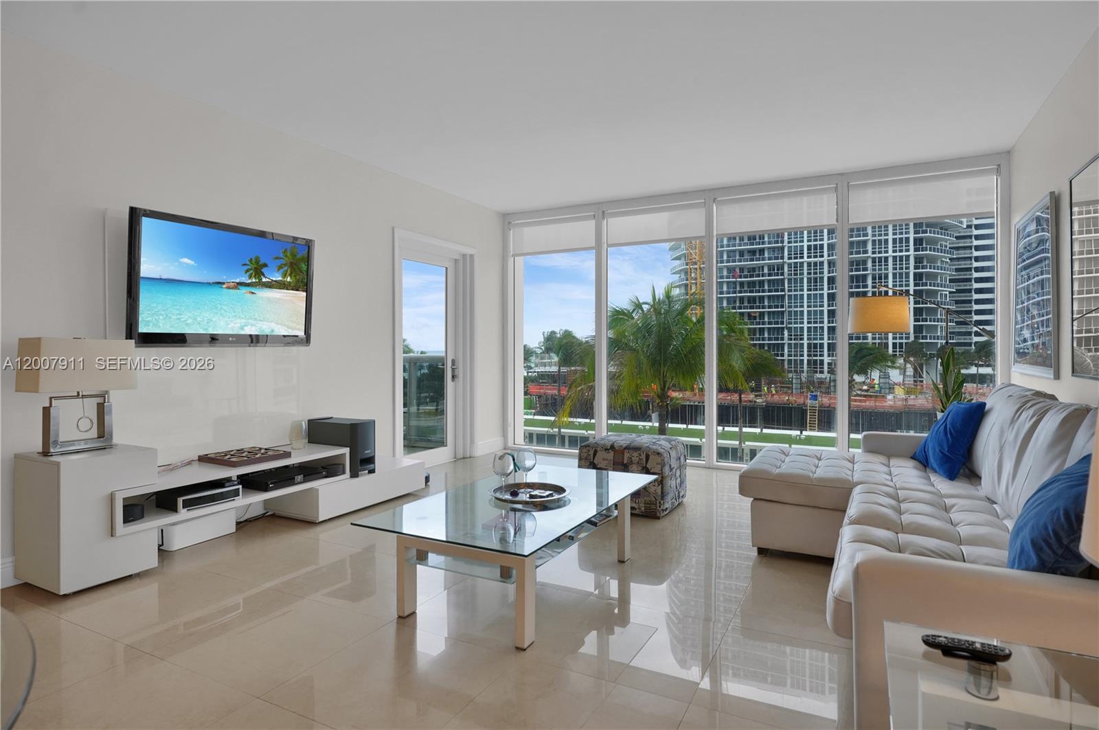 A modern living room features white tile floors, a glass coffee table, and floor-to-ceiling windows — 10275 Collins Ave # 315, Bal Harbour FL 33154, BAL HARBOUR, FL