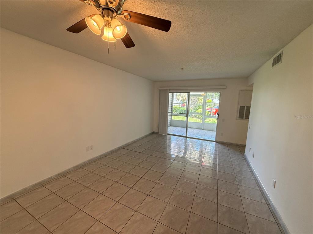A living room features light-colored tile flooring, a ceiling fan, and a sliding glass door — 3900 SOUTHPOINTE DRIVE UNIT 120, ORLANDO, FL