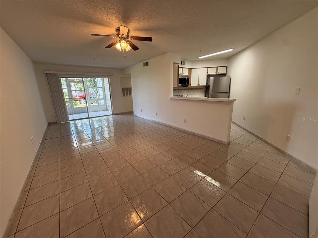 An open-concept living and dining area features light-colored floor tiles and a kitchen pass-through — 3900 SOUTHPOINTE DRIVE UNIT 120, ORLANDO, FL