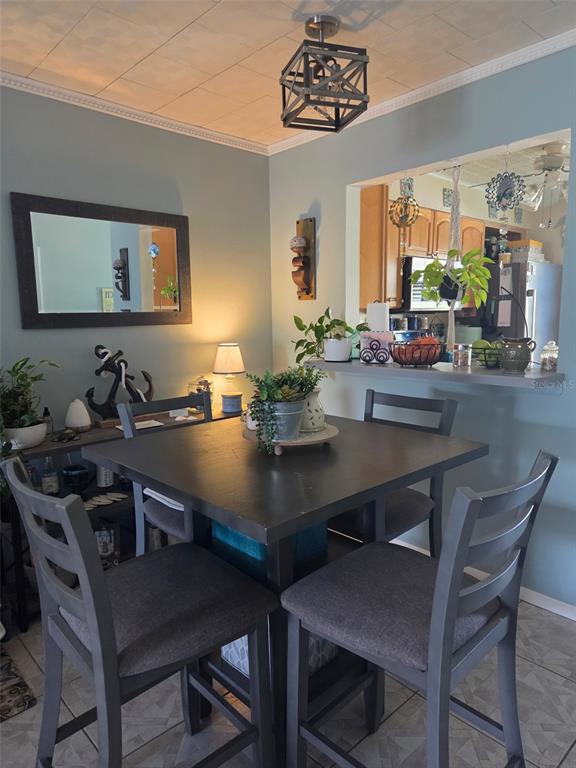 A dining area features a square table with four chairs and a kitchen pass-through window — 13830 MISSION OAKS BOULEVARD UNIT 13830, SEMINOLE, FL