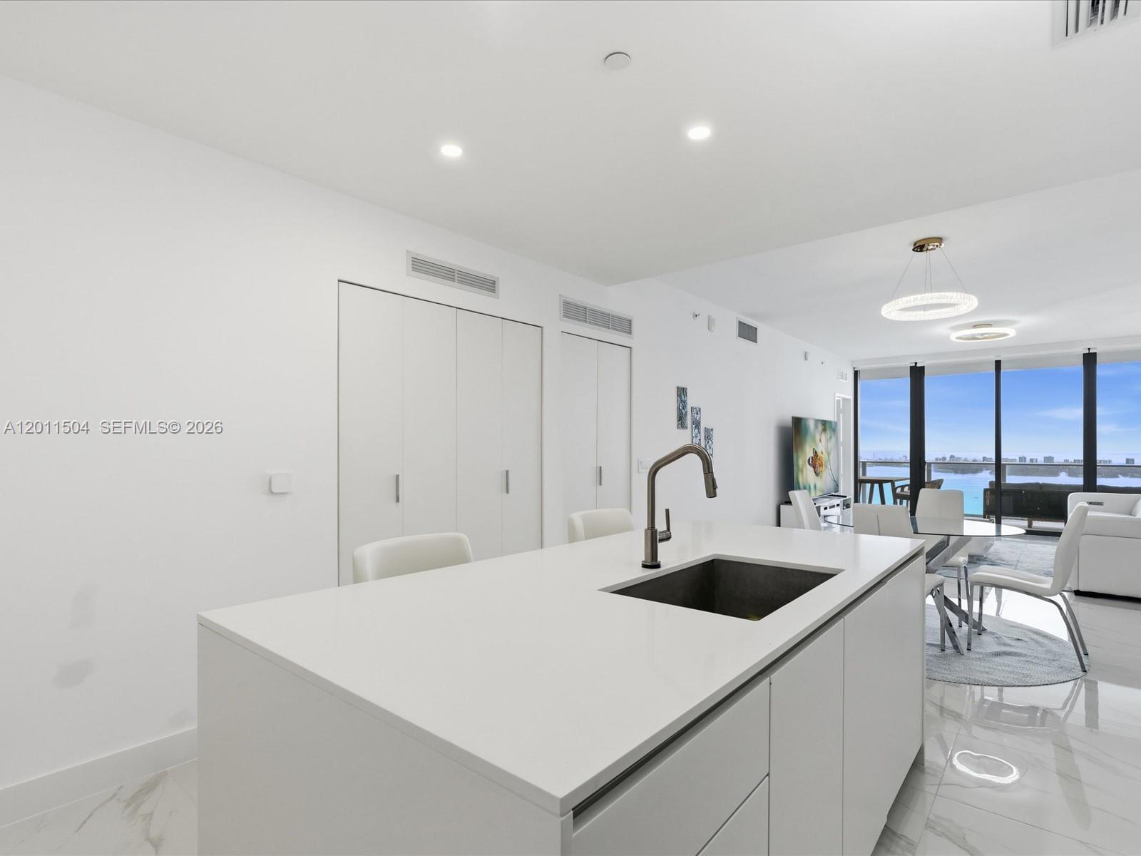 A modern kitchen island with a sink sits in a bright room with white cabinetry — 700 NE 24th Street # 4606, Miami FL 33137, MIAMI, FL