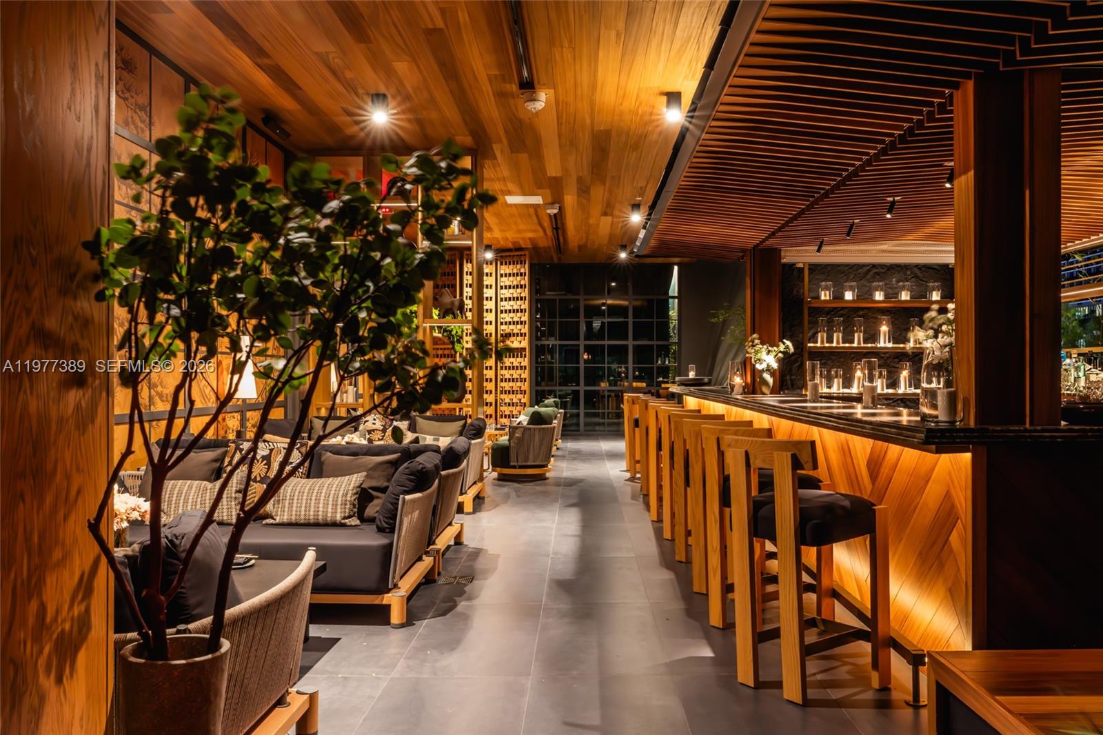 A modern bar area features wooden slat ceilings, bar stools, and lounge seating — 159 NE 6th St # 3713, Miami FL 33132, MIAMI, FL