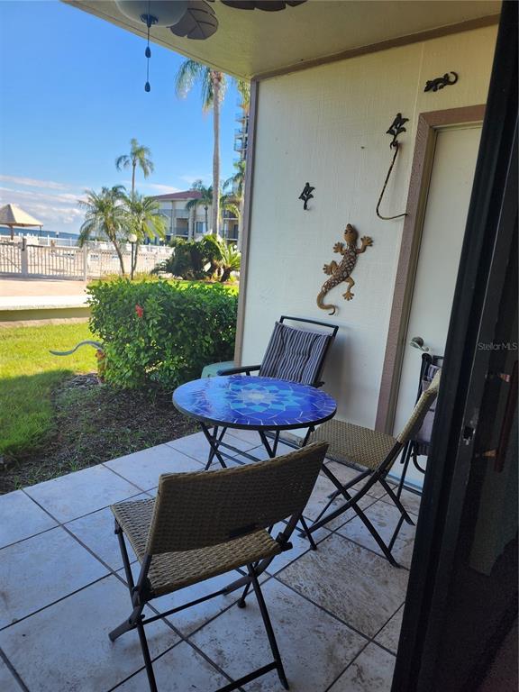 A patio with a mosaic table and chairs overlooks a grassy area and a lake — 6268 PALMA DEL MAR BOULEVARD S UNIT 111, ST PETERSBURG, FL
