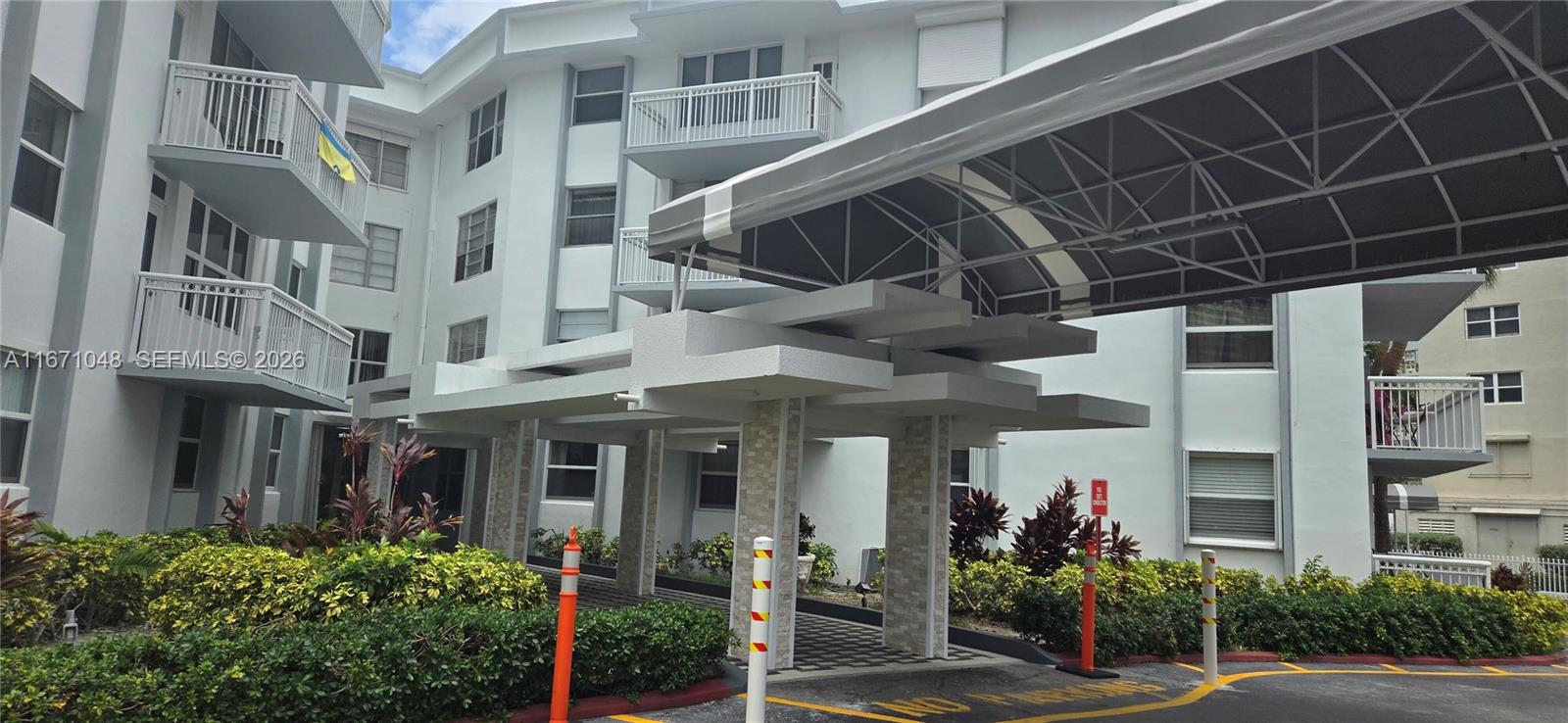 The exterior of a multi-story apartment building features a covered driveway entrance with stone pillars — 1913 S Ocean Dr # 138, Hallandale Beach FL 33009, HALLANDALE BEACH, FL