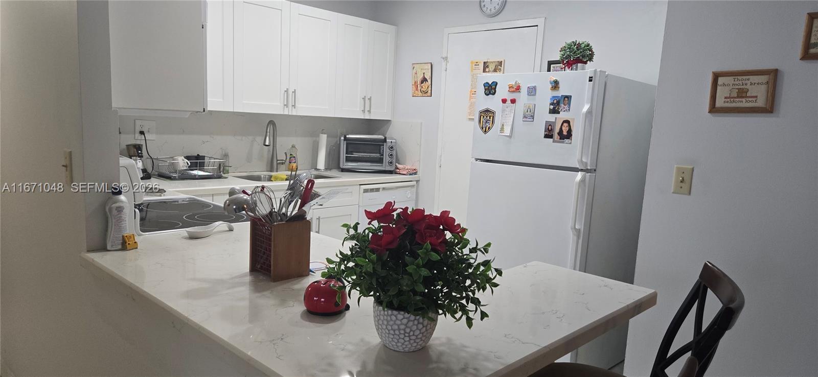 A kitchen features white cabinets, quartz countertops, a white refrigerator, and a breakfast bar — 1913 S Ocean Dr # 138, Hallandale Beach FL 33009, HALLANDALE BEACH, FL