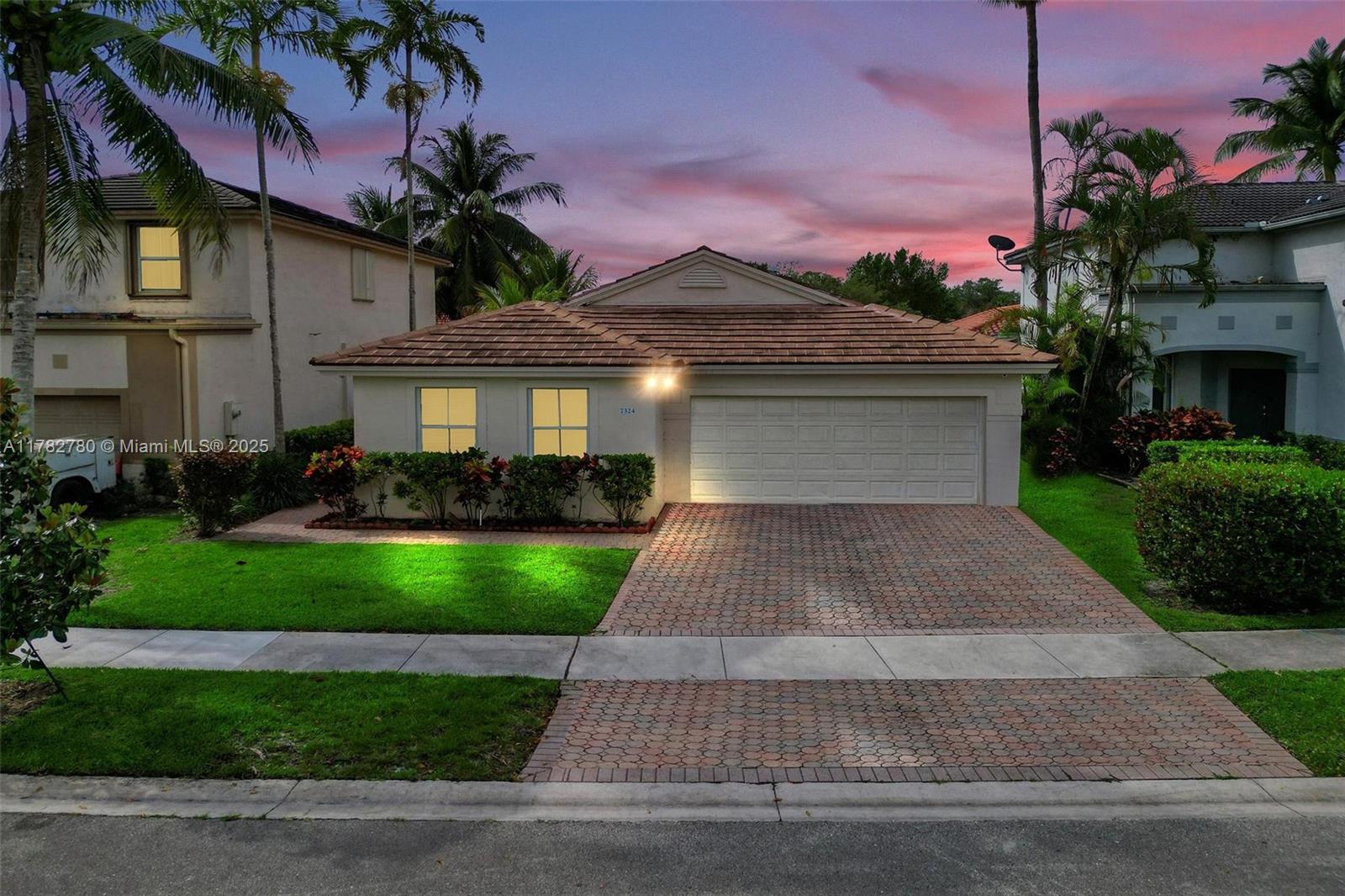 A single-story house with a tiled roof, a paved driveway, and palm trees at dusk — 7324 NW 1st Pl, Plantation FL 33317, PLANTATION, FL