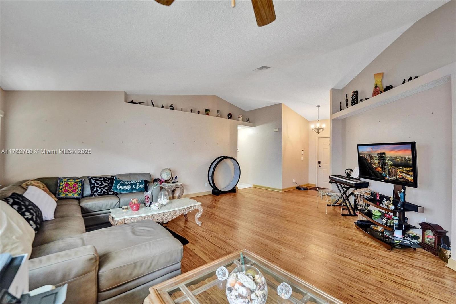 A living room features a sectional sofa, wood-look flooring, and a vaulted ceiling — 7324 NW 1st Pl, Plantation FL 33317, PLANTATION, FL