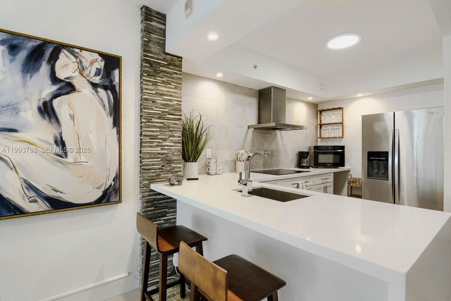 A modern kitchen features white countertops, a stone accent wall, and stainless steel appliances — 2501 S Ocean Dr, Hollywood FL 33019, HOLLYWOOD, FL