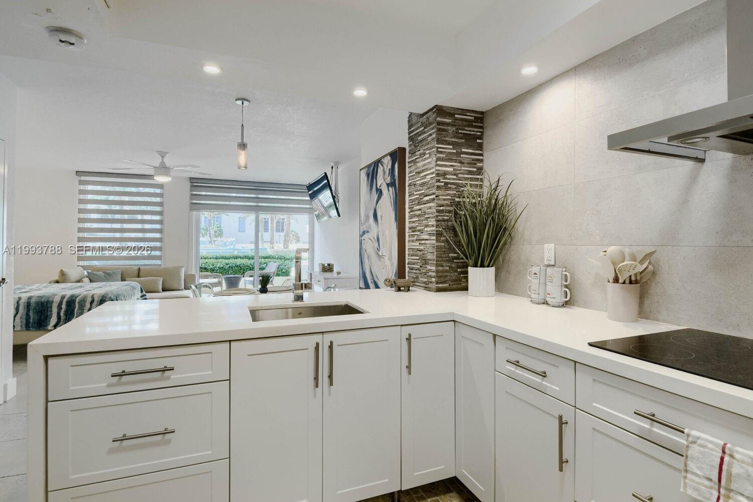 A modern kitchen features white cabinets, quartz countertops, and a stone-tiled accent wall — 2501 S Ocean Dr, Hollywood FL 33019, HOLLYWOOD, FL